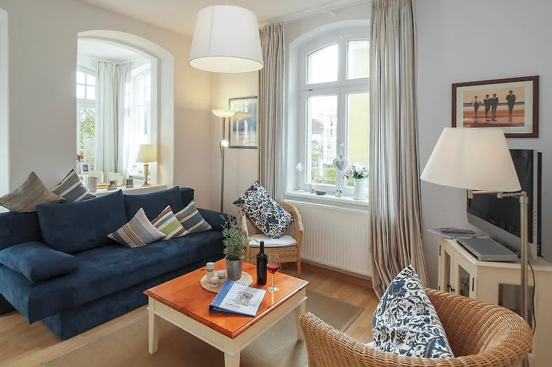 Wohnzimmer mit Schlafcouch und Korbsesseln