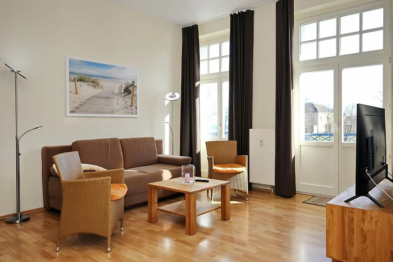 Wohnzimmer mit Schlafcouch und Korbsesseln
