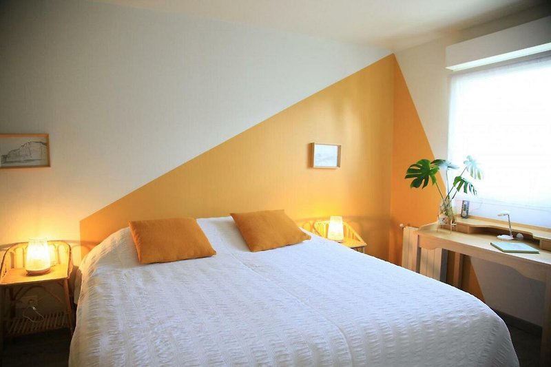 Une chambre confortable avec un lit en bois et une lampe orange.
