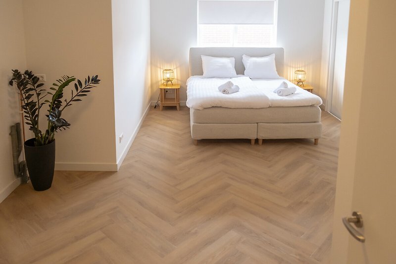 Helles Schlafzimmer mit Holzfußboden und Tagesbett.