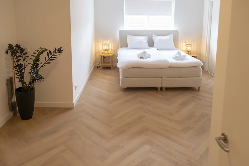 Helles Schlafzimmer mit Holzfußboden und Tagesbett.