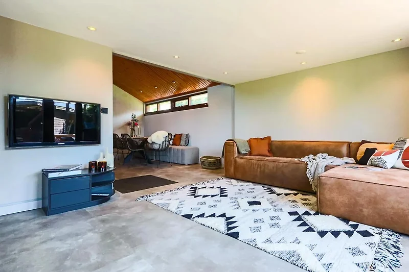 Wohnzimmer mit Sofa, Fernseher und Holzdekor.