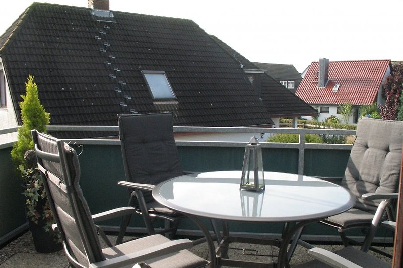 Balkon mit Tisch und vier klappbaren Stühlen