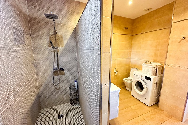 Modernes Badezimmer mit Dusche, Waschmaschine und Trockner.