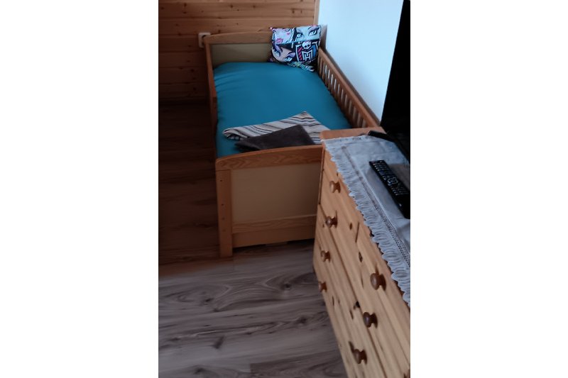 Gemütliches Schlafzimmer mit Holzmöbeln und gemusterten Bettwäsche.