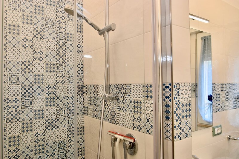 Un bagno moderno con piastrelle di ceramica, doccia a pioggia e accessori eleganti.
