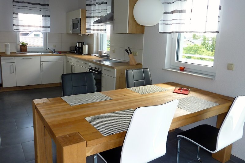 Moderne Küche mit Holzmöbeln und großen Fenstern.