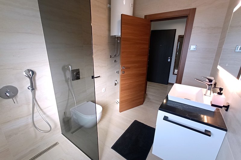 Modernes Badezimmer mit eleganten Armaturen, Glasdusche und stilvoller Beleuchtung.