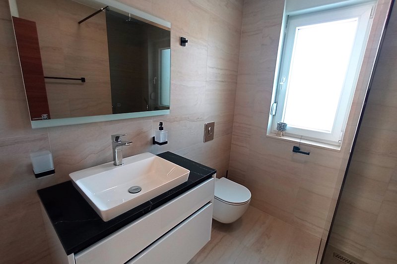 Modernes Badezimmer mit braunem Waschbecken und Fenster.
