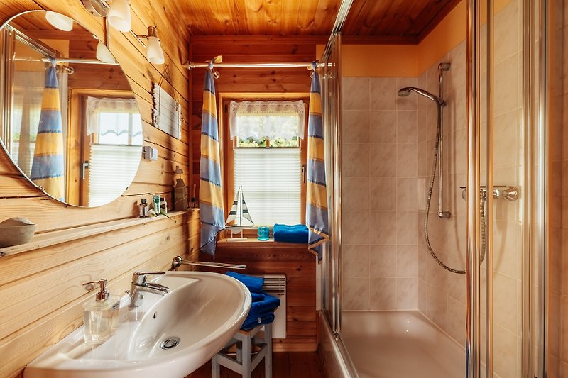 Spiegel, Wasserhahn, Waschbecken, Fenster und Dusche in modernem Badezimmer.