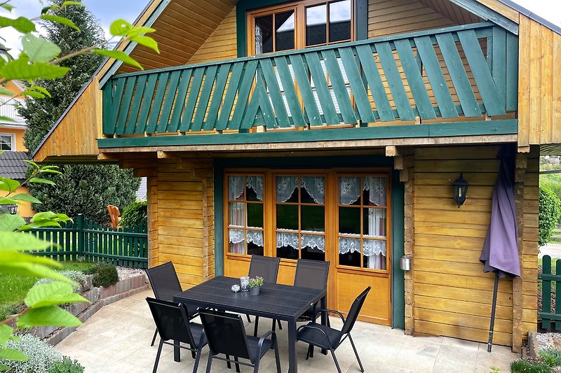 Schönes Ferienhaus mit Holzmöbeln, Tisch und Pflanzen.