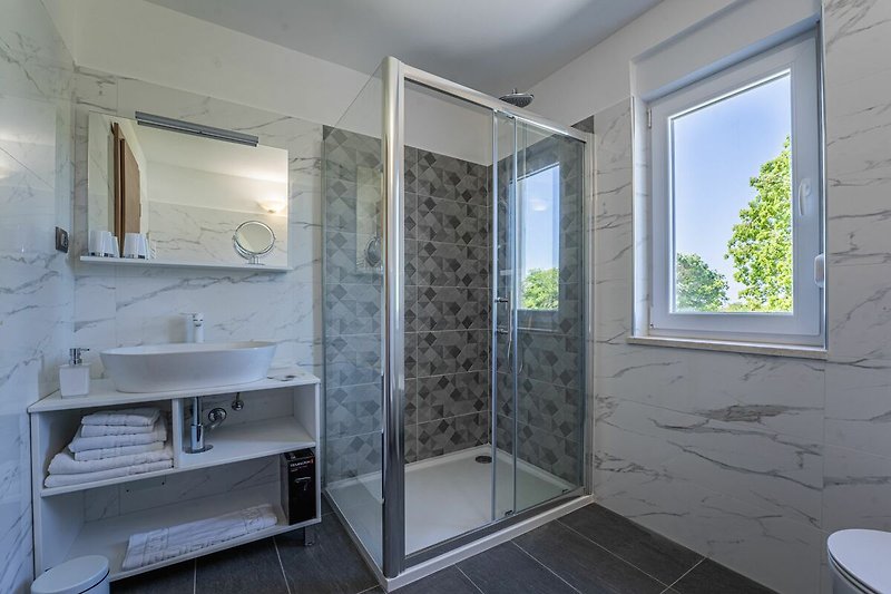 Badezimmer mit stilvoller Dusche und Fenster.
