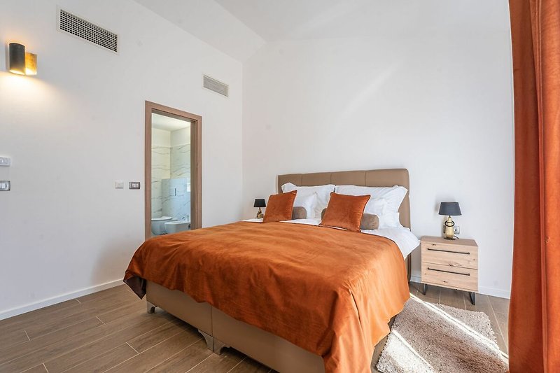 Gemütliches Schlafzimmer mit Holzmöbeln und orangefarbenen Kissen.