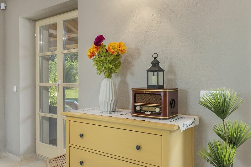 Schönes Zimmer mit Holzmöbeln, Blumen und gelber Dekoration.