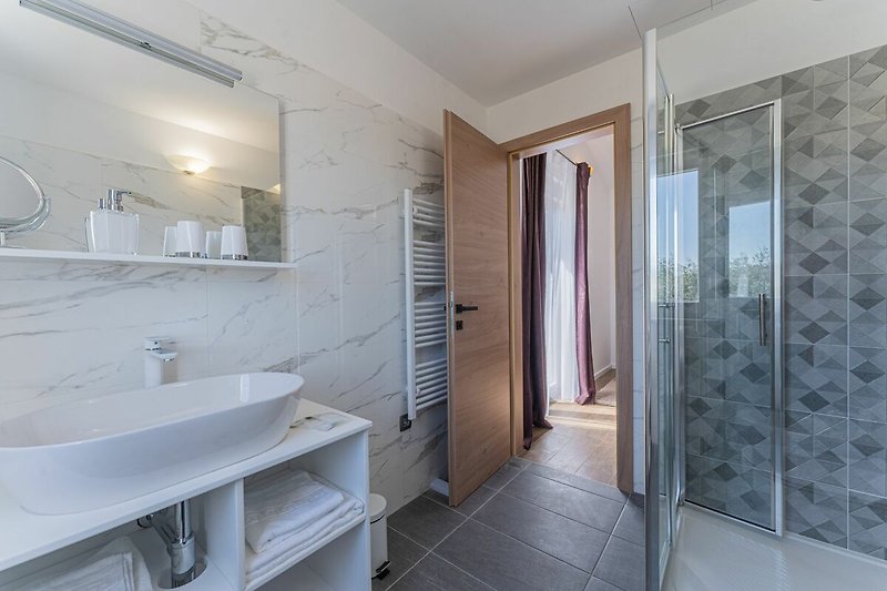 Moderne Badezimmer mit stilvoller Dusche, Waschbecken und Fenster.