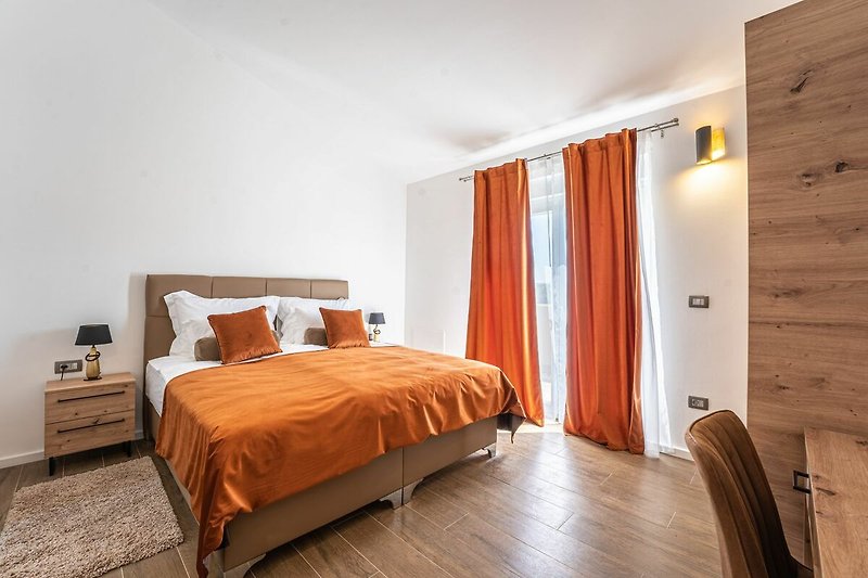 Gemütliches Schlafzimmer mit Holzmöbeln und orangefarbenen Vorhängen.