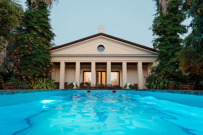 Villa mit Pool, Wasserfeature und schattigem Sitzbereich.