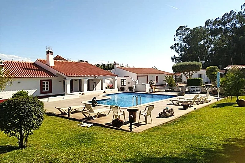 Villa mit Swimmingpool und schöner Rasenfläche in einem gepflegten Garten mit Sonnenliegen und schattigen Plätzen.