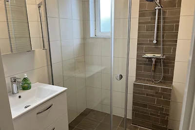 Badezimmer im Erdgeschoss mit ebenerdiger Dusche, Waschtisch und Fenster Badezimmer im Erdgeschoss mit ebenerdiger Dusche, Waschtisch und Fenster