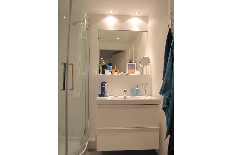 Shower bath with washbasin and floor-to-ceiling towel radiator.