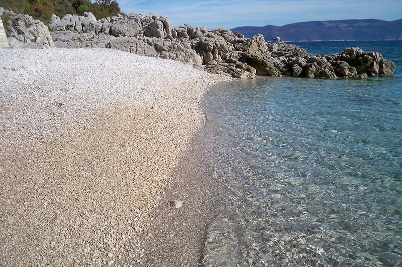 Typischer Kleinkies-Strand mit kristallklarem Wasser