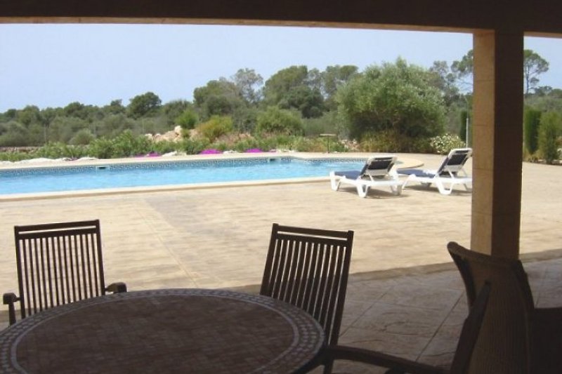 Blick auf den Pool vom 50 qm grossen Poolhaus mit Tischen, Stühlen und WLAN