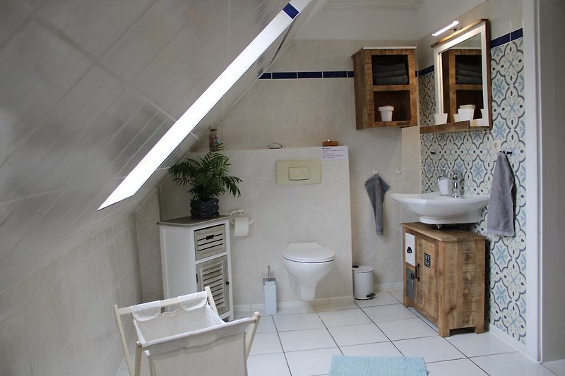 Badezimmer mit modernem Design, Spiegel, Waschbecken, Toilette und Pflanze.