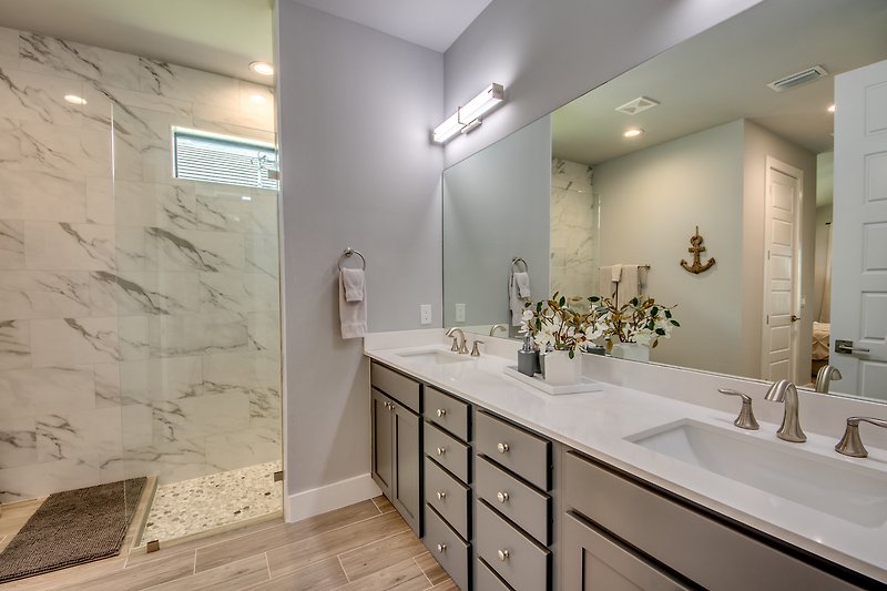 Schönes Badezimmer mit Spiegel, Waschtisch und modernem Wasserhahn.