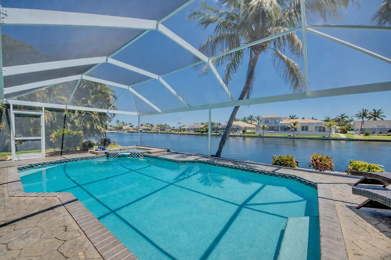 Weitläufige Villa mit Pool, Palmen, schattigen Plätzen und Wasserbecken.