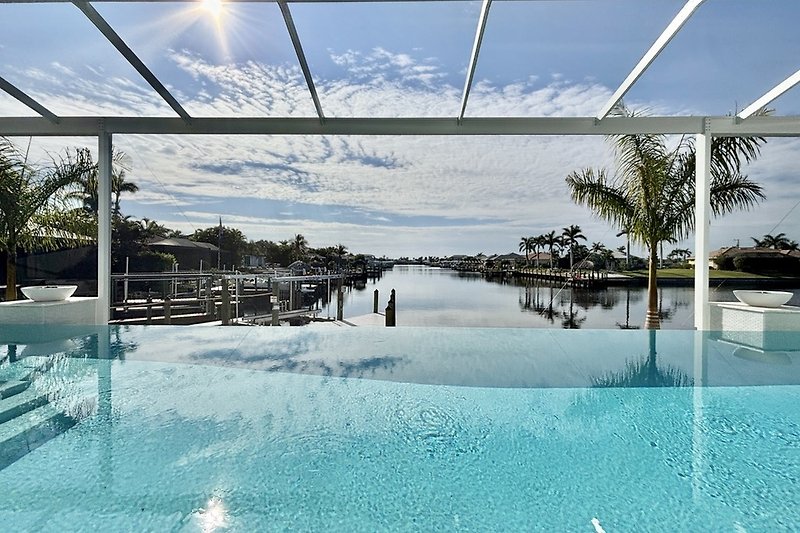 Entspannen Sie am Pool mit Palmen und schattiger Pergola.