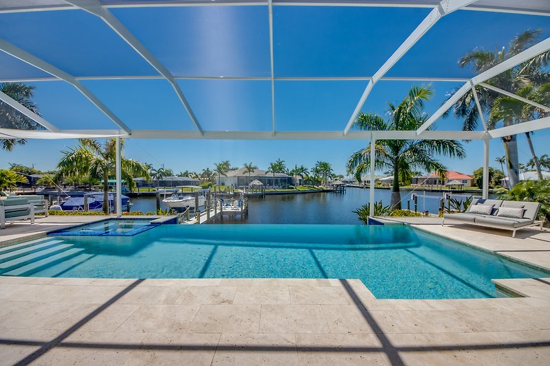 Luxuriöses Ferienhaus mit Pool und Palmen in sonniger Umgebung.