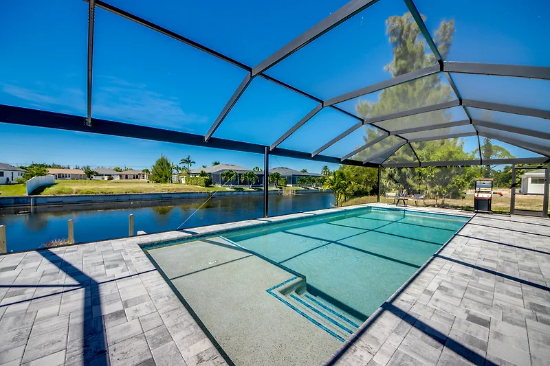 Reflektierender Pool mit Wasserlauf, Designvilla und schattiger Pergola.