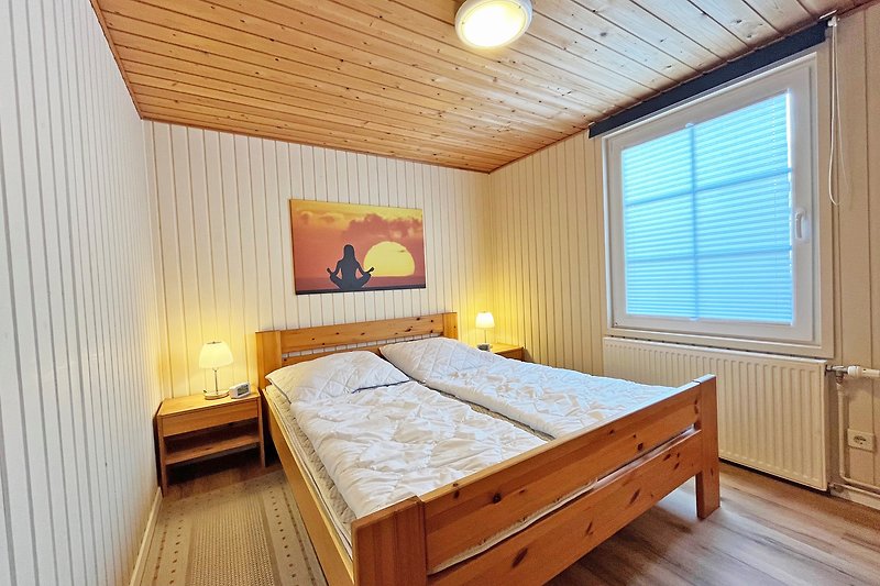 Schlafzimmer 1 mit gemütlichem Bett, Holzmöbeln und Lampen.