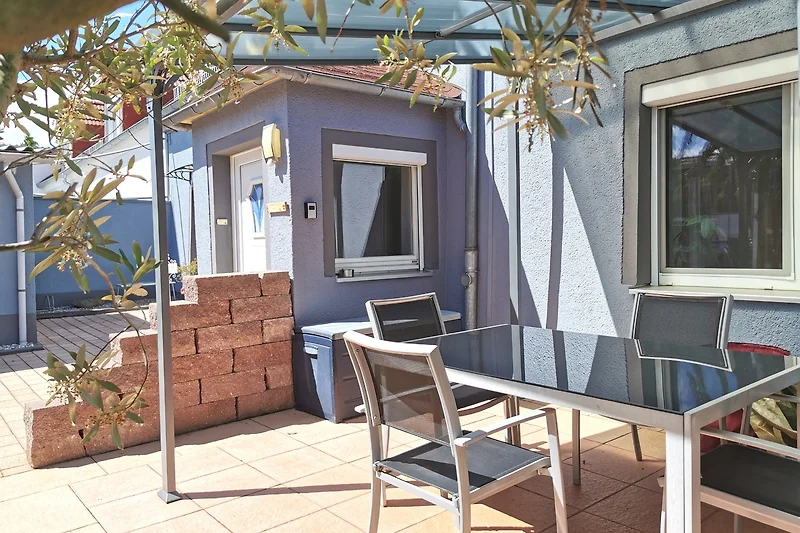 Tisch und Stühle im begrünten Innenhof mit Blumentöpfen.