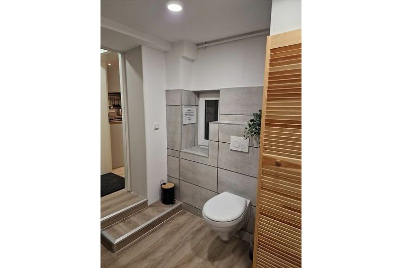 Badezimmer mit Holzfußboden, Fenster und Waschbecken.