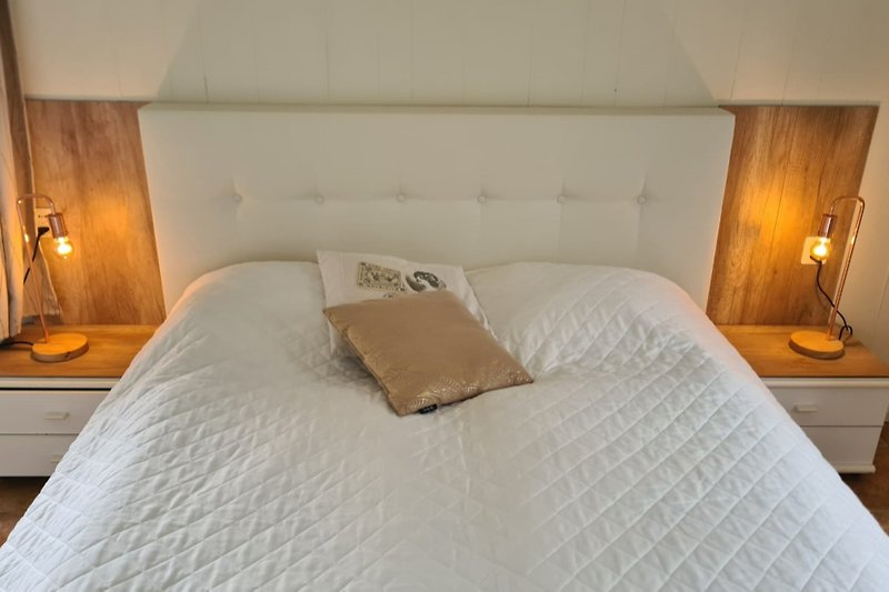 Stilvolles Schlafzimmer mit gemütlichem Bett und elegantem Lampenlicht.