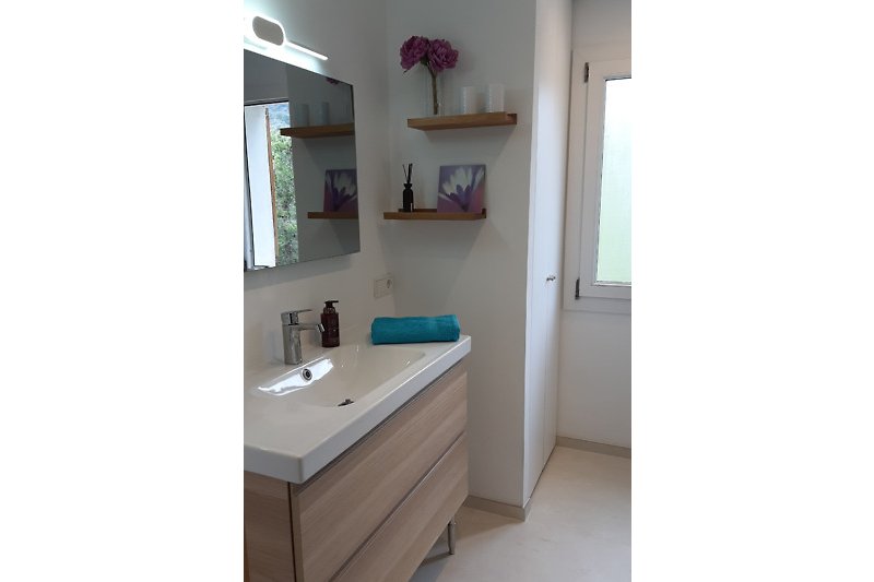Badezimmer mit Spiegel-Infrarot-Heizung, Waschbecken und Armatur.