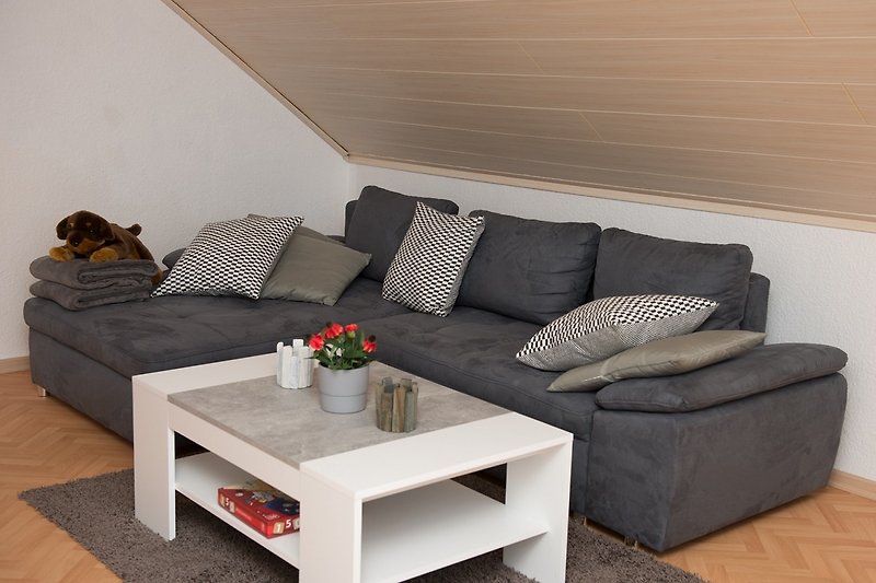 Gemütliches Wohnzimmer mit bequemer Couch und stilvollem Holzmöbel.