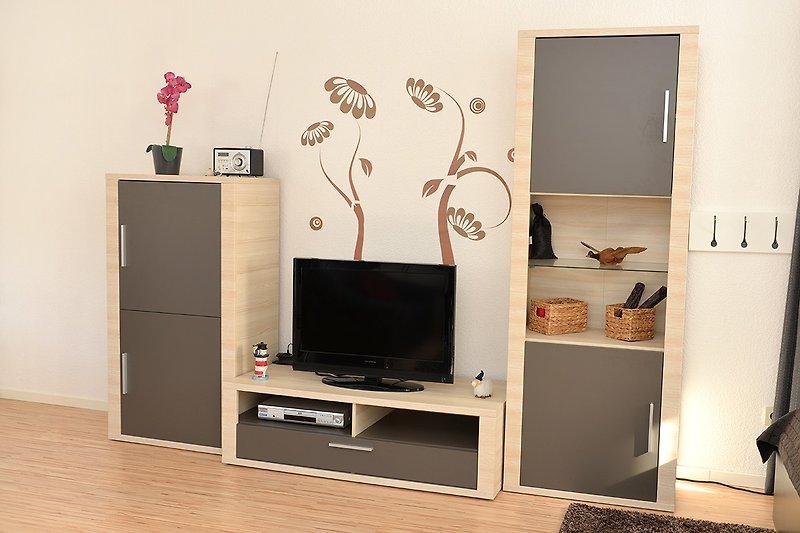 Stilvolles Wohnzimmer mit Holzmöbeln, Kunst und modernem Fernseher.