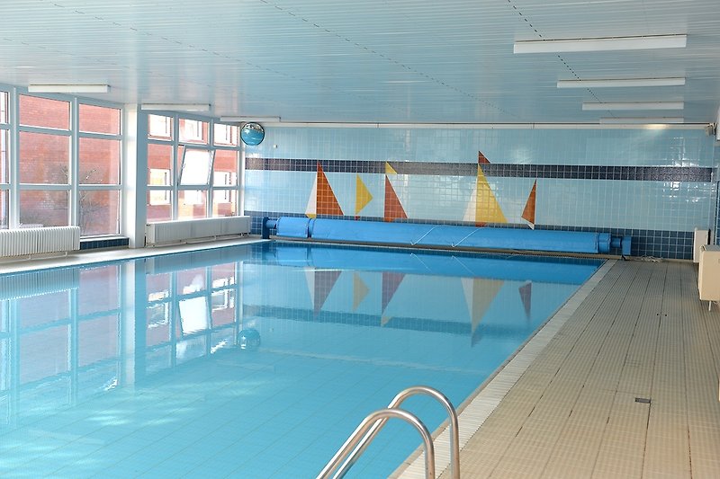 Schwimmbecken mit azurblauem Wasser und Blick auf das Gebäude.