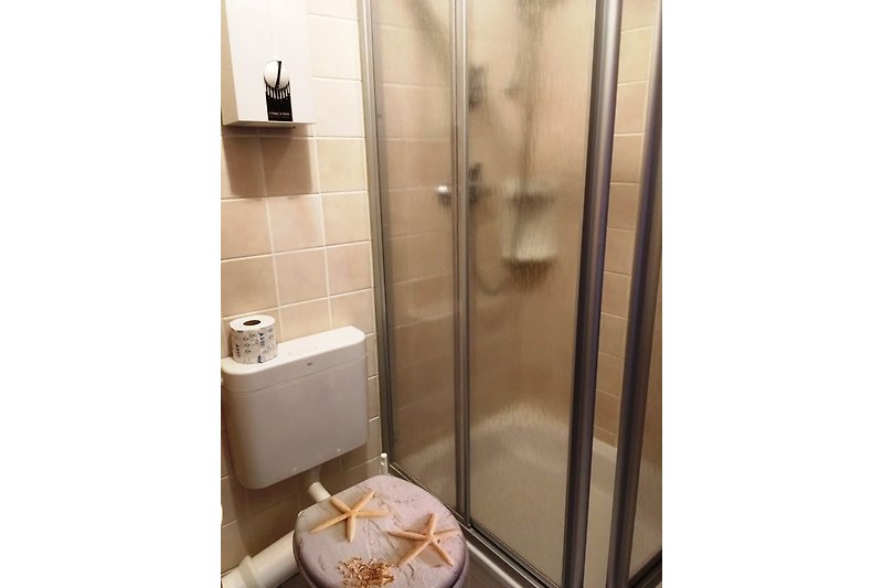Schönes Badezimmer mit weißer Duschtür, Fenster und Keramikfliesen.