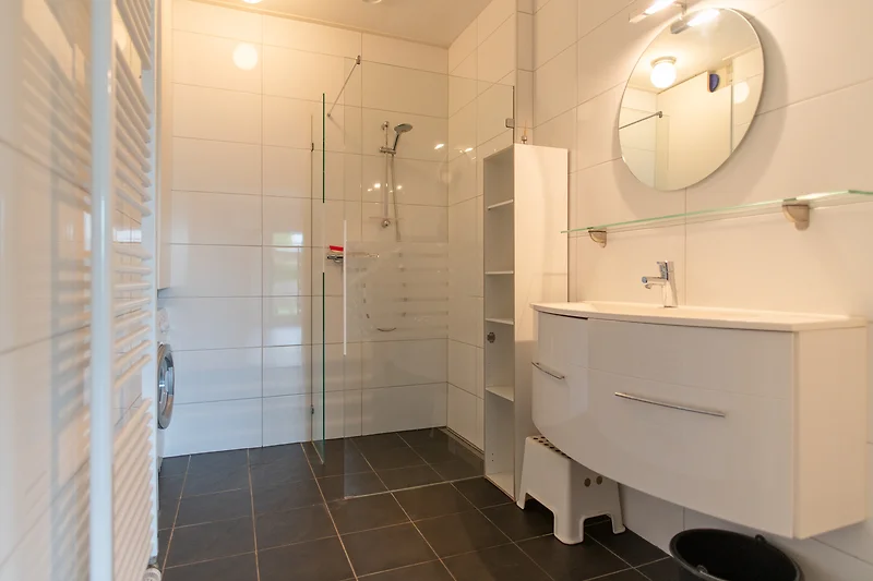 Hochwertiges Bad mit großer Dusche, Spiegel, Pflanzen und viel Stauraum.