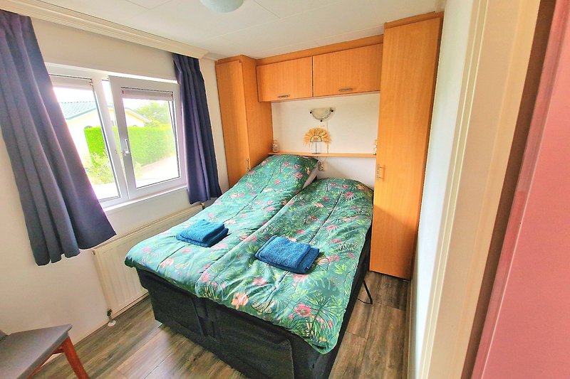 Prachtige slaapkamer met houten bedframe, gordijnen en comfortabele beddengoed.