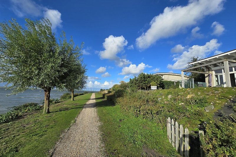 Charmantes Landhaus mit Garten und Blick auf Hügel und Wolken.