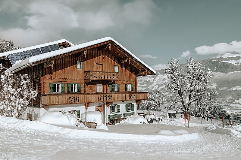 Gemütliches Haus mit Fenstern, Schnee und Berglandschaft. Perfekt für den Winterurlaub.