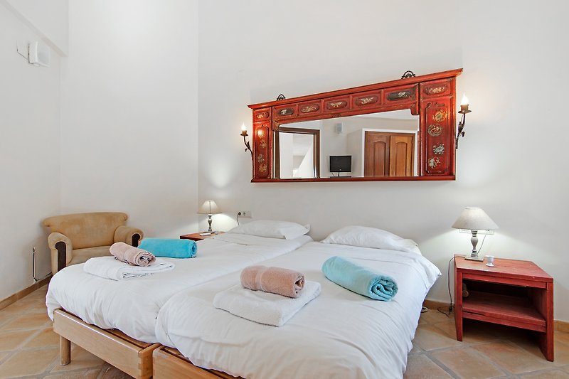 Schlafzimmer mit bequemem Bett, Spiegel und Holzmöbeln. Gemütliche Atmosphäre.