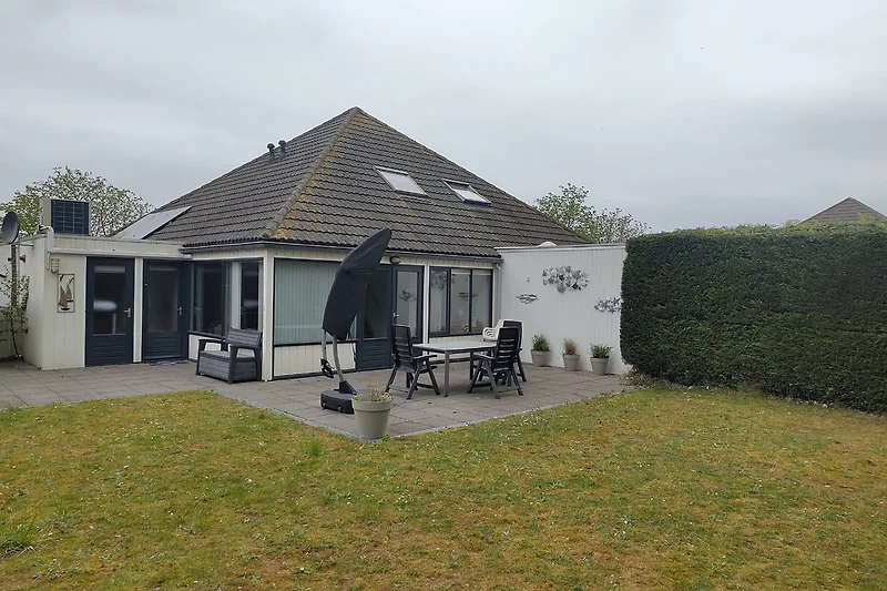 Großes Haus mit gepflegtem Garten, Einfahrt und überdachter Terrasse.