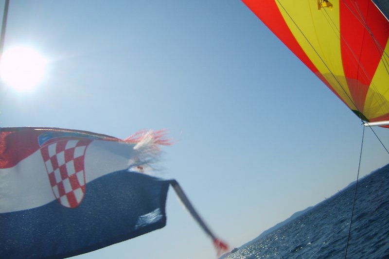 Blaue Flagge am Bootspfahl, Wolken am Himmel, Boote auf dem Wasser.