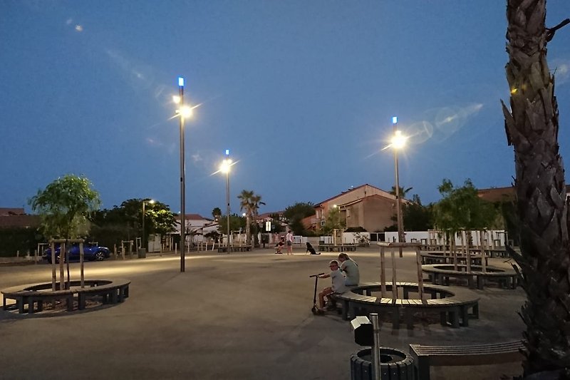 Schöner Ausblick auf das "quartier der Ferienwohnung" bei Sonnenuntergang mit Palmen und Straßenbeleuchtung.