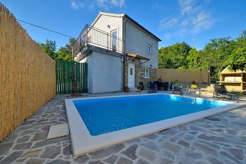 A beautiful property with a swimming pool, surrounded by lush greenery and outdoor furniture.